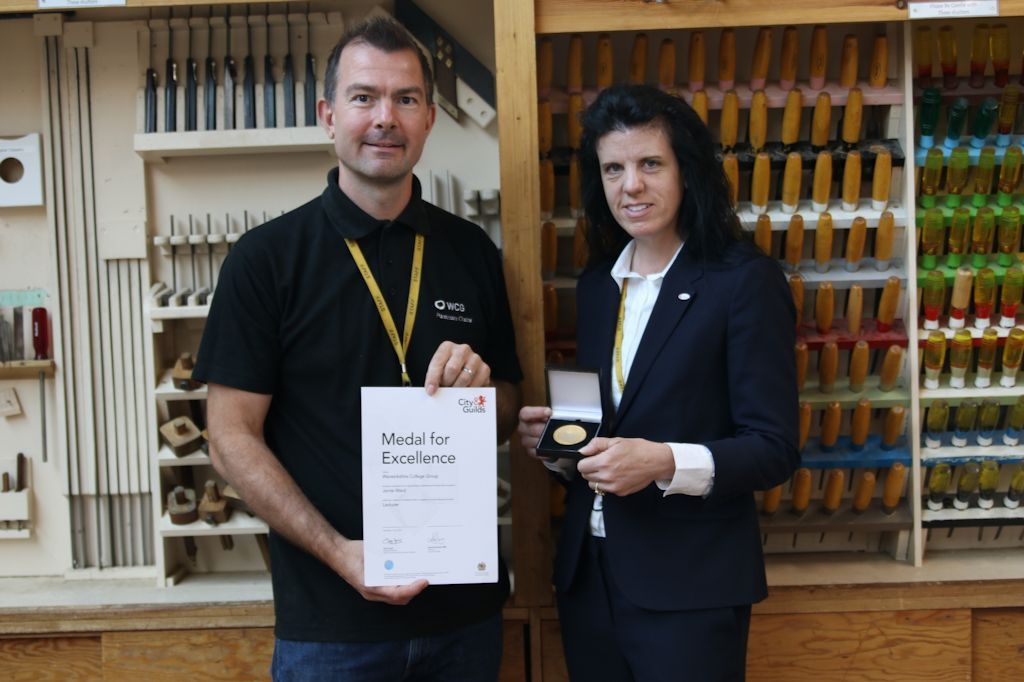 amie received his medal by Angela Joyce, CEO of WCG in the college’s furniture crafts workshop.